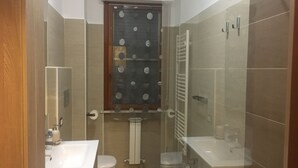 Ein modernes Badezimmer mit Duschkabine aus Glas, Toilette, Waschbecken und Spiegel.