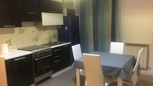 Eine kompakte Küche mit Esstisch und Stühlen, inklusive eingebautem Backofen und Mikrowelle.