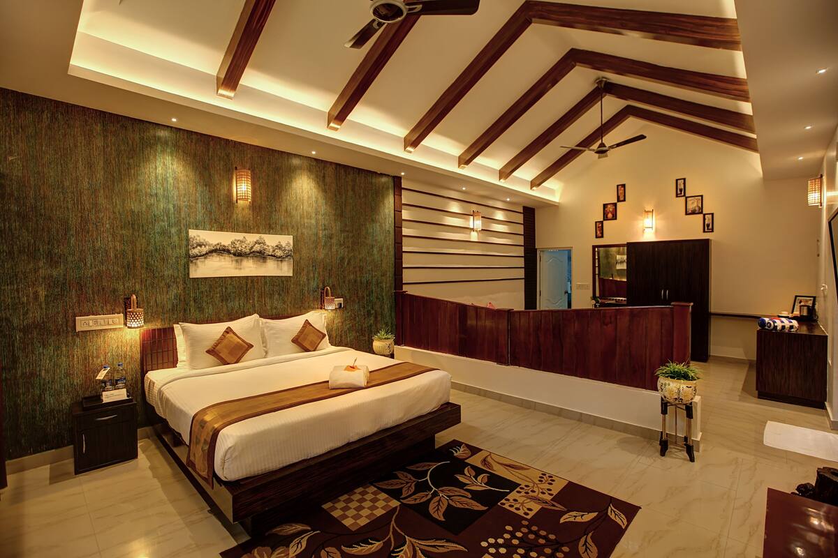 Quarto de hotel moderno com uma cama grande, uma receção e uma varanda pequena.