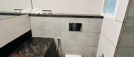 Une salle de bain moderne avec un plan de toilette en marbre, des toilettes, un porte-serviettes et une douche.