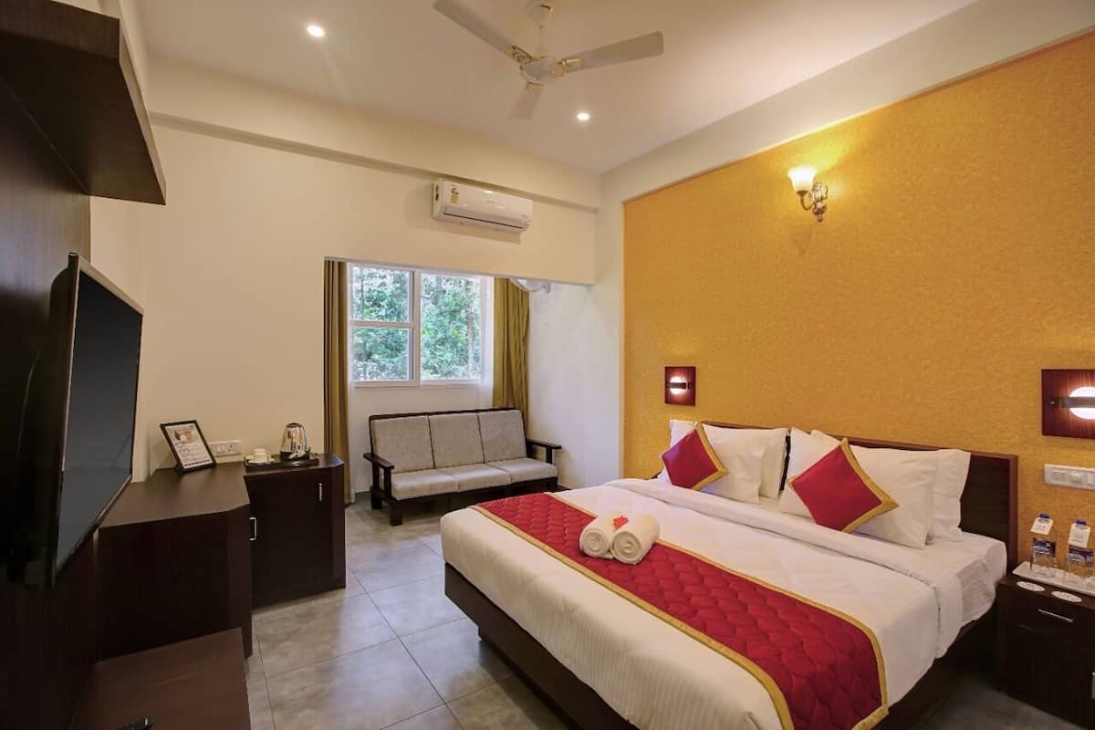 Quarto de hotel com cama, sofá, televisão e secretária.