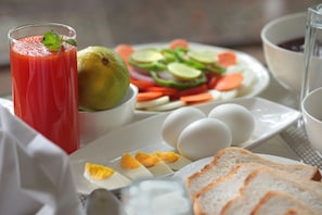 A breakfast setting with a glass of red juice, eggs, toast, and a salad. - Gokulam Grand Resort and Spa Coorg (Somvarpet)