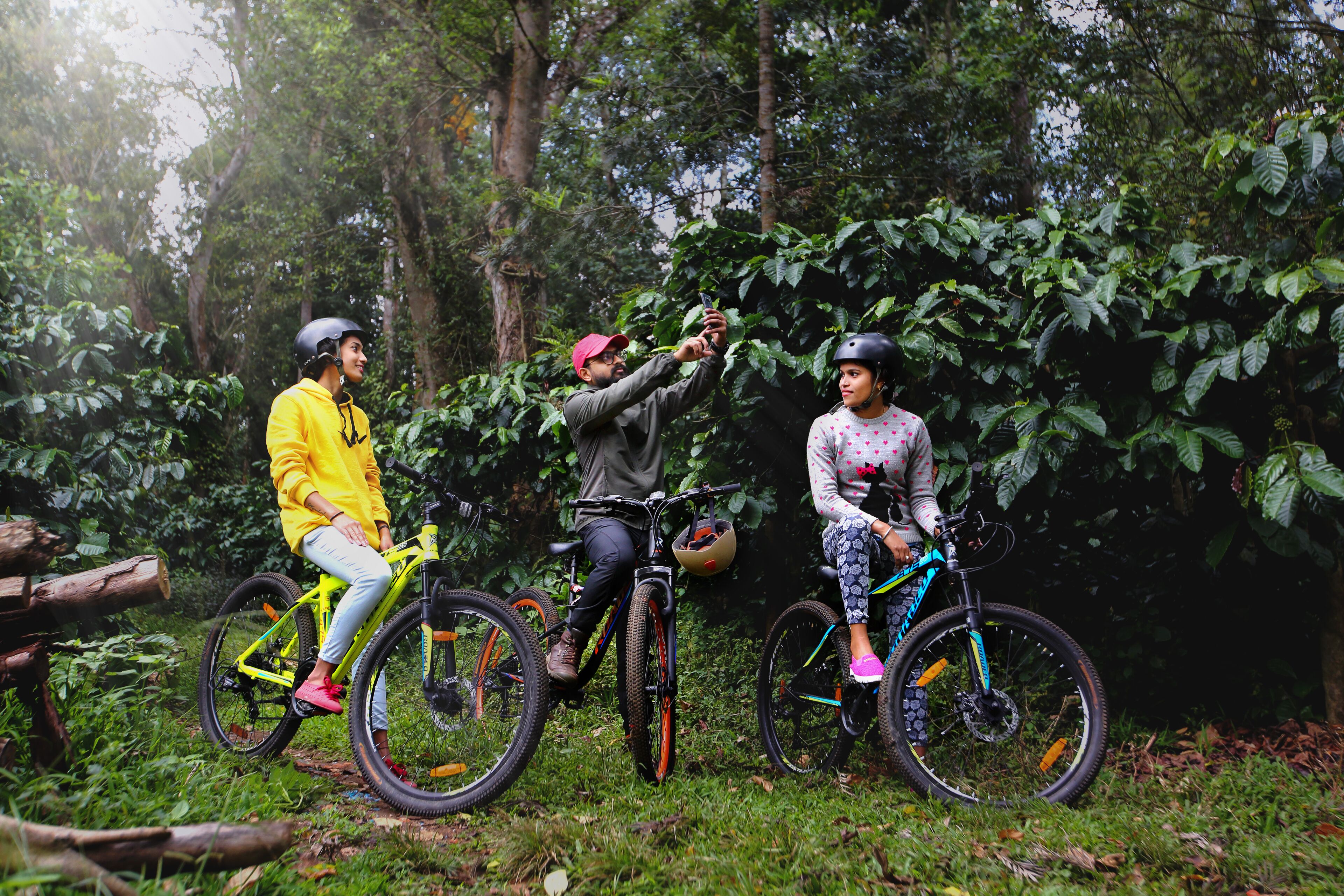 Tres personas en bicicleta en un área boscosa.