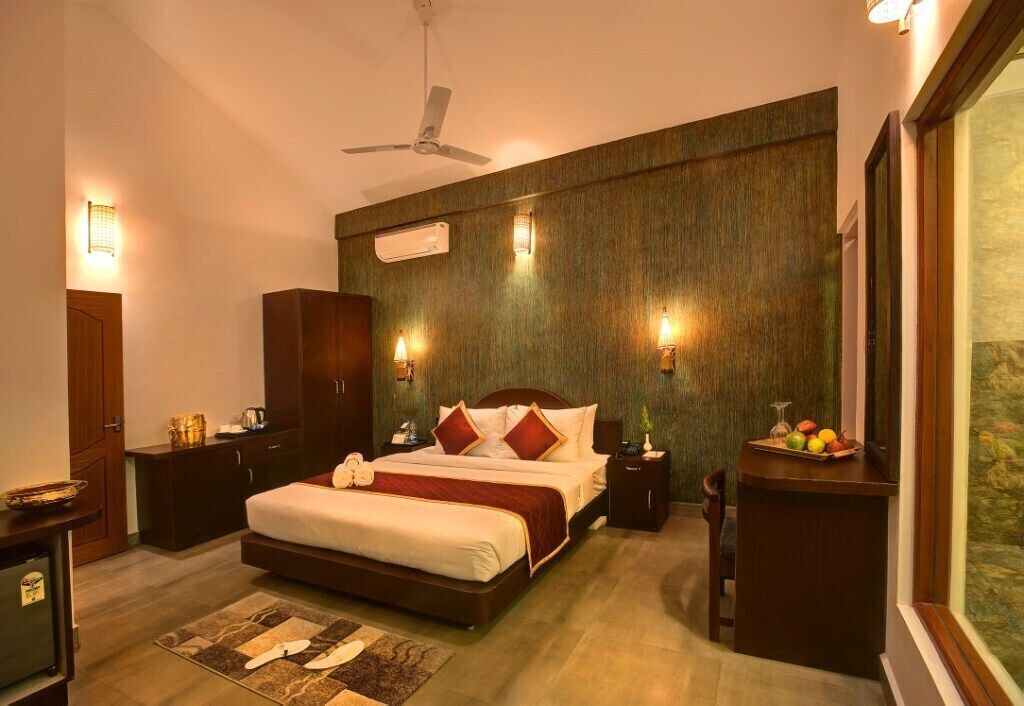 A well-lit bedroom with a large bed, a ceiling fan, bedside tables, and a nightstand with a fruit bowl.