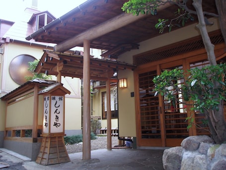A traditional Japanese building with a wooden entrance, a stone lantern, and a sign with Japanese characters.