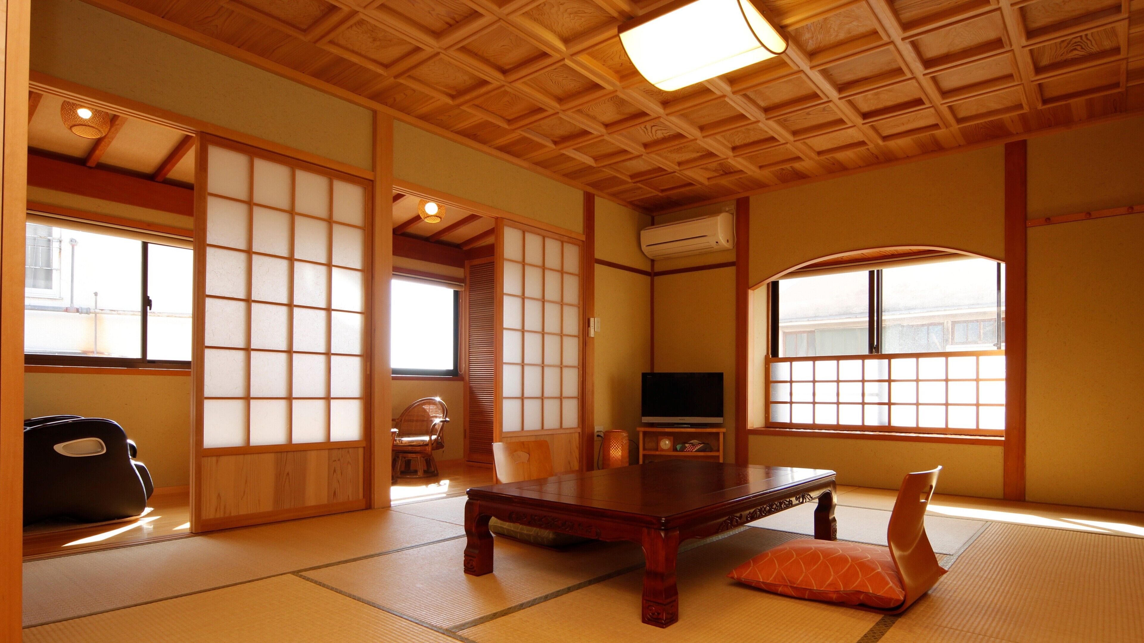 A traditional Japanese room with tatami flooring, a low wooden table, a television, and sliding doors.