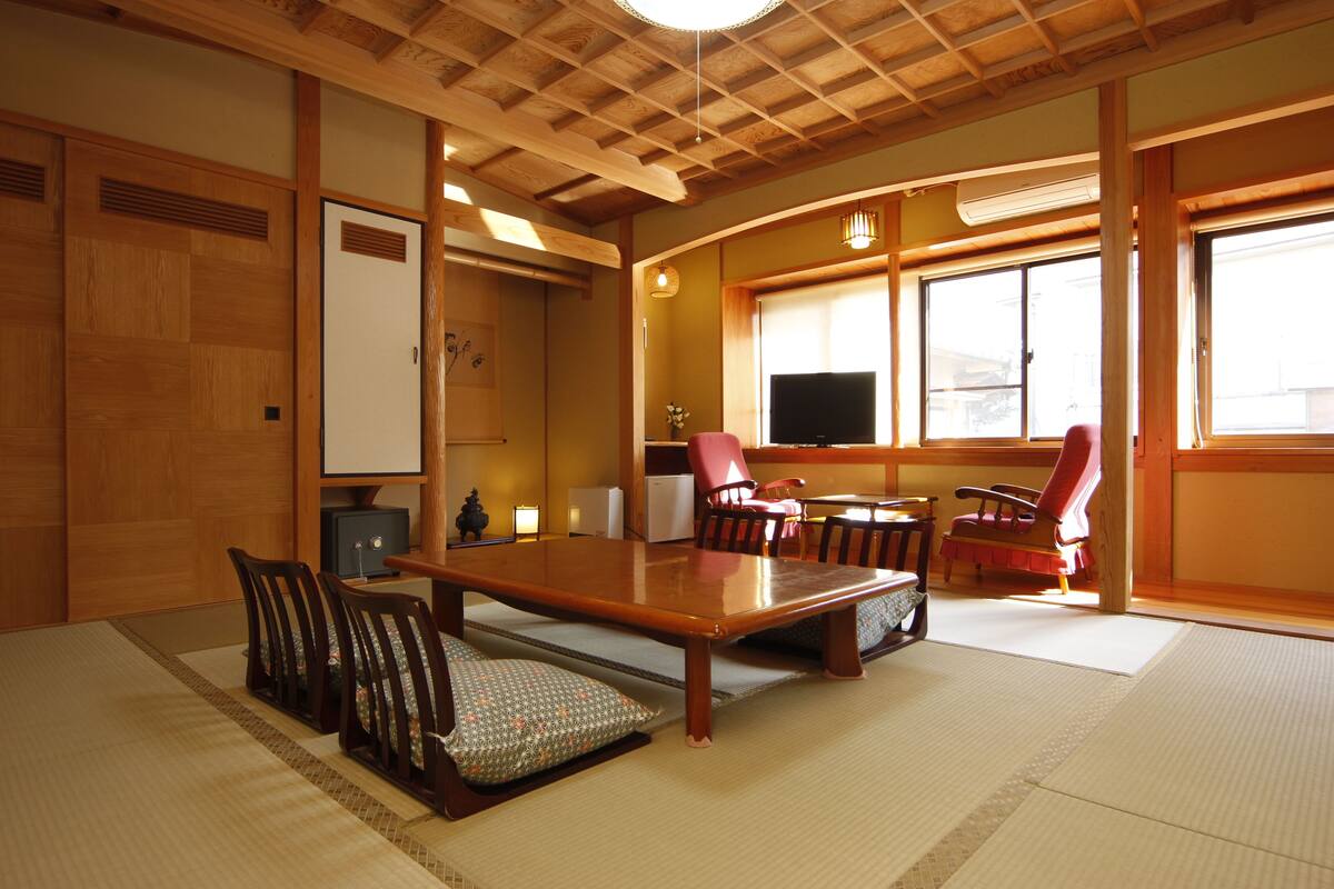 A traditional Japanese-style room with tatami flooring, a low table, and wooden furniture.