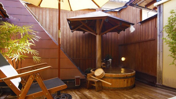 Een houten terras met een hottub, een houten stoel en een kleine tafel.