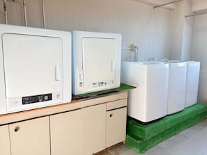 A laundry area with multiple washing machines, a sink, and a green mat.