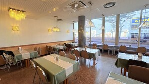 A restaurant with multiple tables and chairs, large windows, and ceiling fans. - APA Hotel Okhotsk Kitami (Kitami)