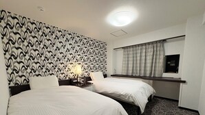 A hotel room with two beds, a desk with a computer, a mirror, and a patterned carpet. - APA Hotel Okhotsk Kitami (Kitami)