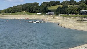 Eine Küstenlandschaft mit Sandstrand, Booten und einem Gebäude im modernen Stil.