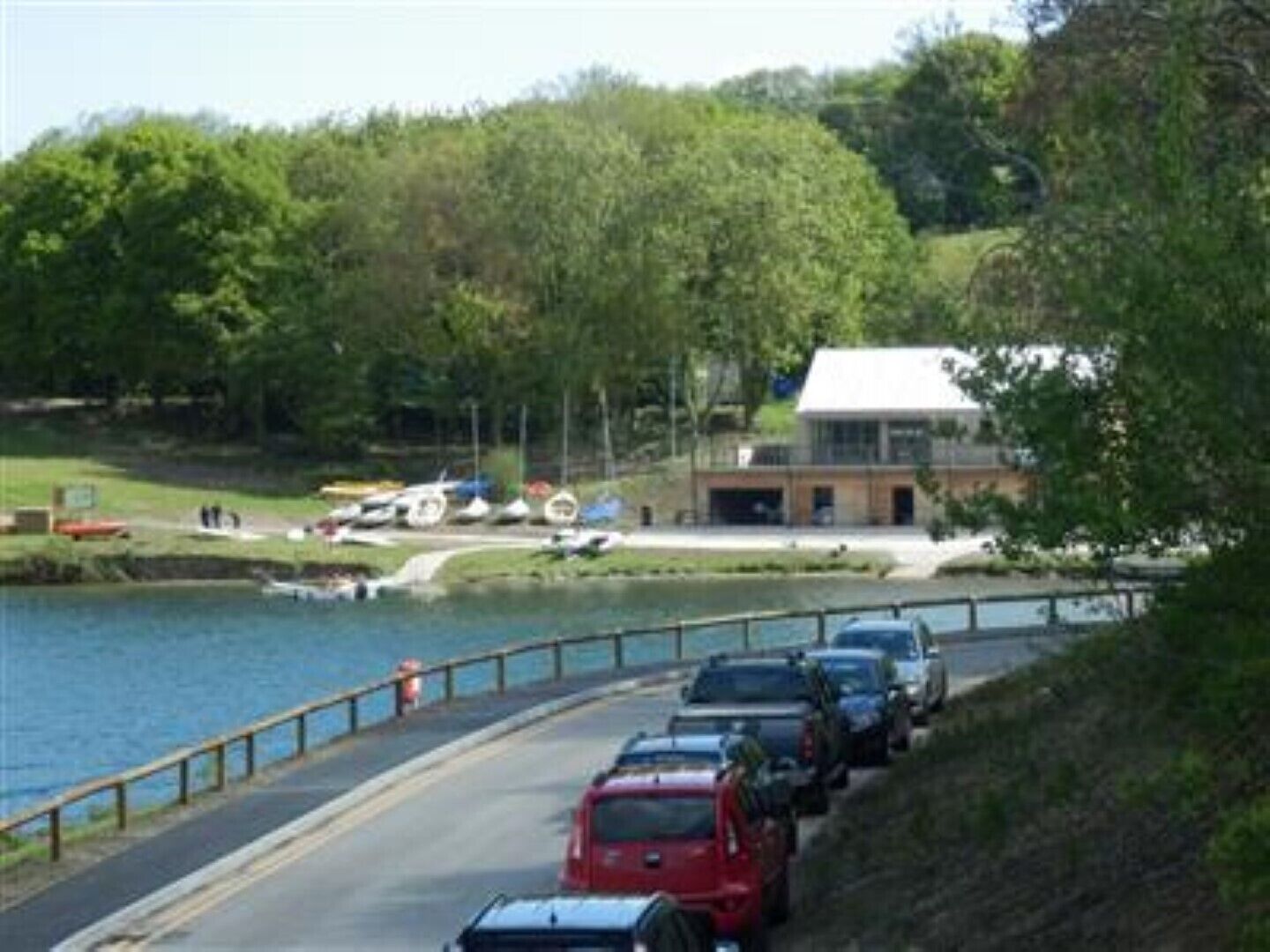 A parking area adjacent to a body of water with a building in the background.