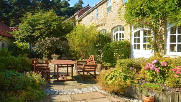 A stone building with a garden patio, wooden furniture, and potted plants. - The Old Farmhouse
3 bed cottage Hot Tub, Dog/cat friendly  onsite fishing (Pickering)