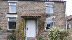 A stone building with a white door, two windows on the upper floor, and a small porch area with plants. - The Old Farmhouse
3 bed cottage Hot Tub, Dog/cat friendly  onsite fishing (Pickering)