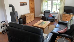 A living room with a sofa, a wooden coffee table, a fireplace, a television, and a window with curtains.