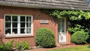 A brick house with a white window, a door, and a sign reading 'Haus Brigitte.'