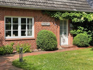 A brick house with a white window, a door, and a sign reading 'Haus Brigitte.'