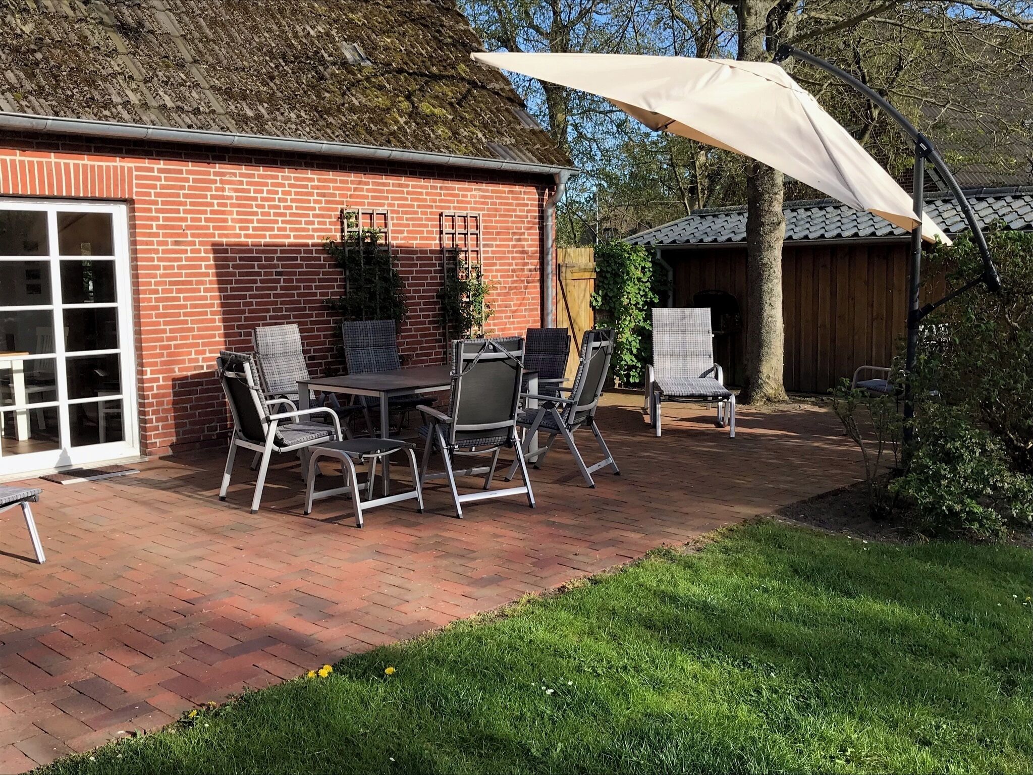 A patio with a brick wall, a table with chairs, and a large umbrella.
