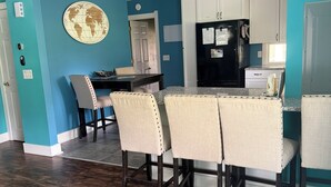 Un comedor con piso de madera, un tapete a rayas y una mesa con cuatro sillas.
