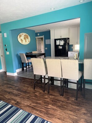 A dining area with a wooden floor, a striped rug, and a table with four chairs.