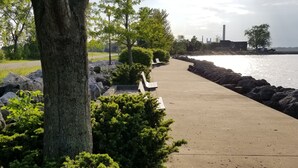 Un paseo marítimo de concreto junto a la costa, con rocas y vegetación.