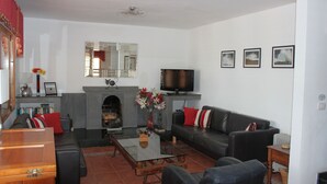 Een woonkamer met een open haard, een bank, een televisietoestel en een salontafel.