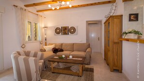 A living room with a sofa, armchair, and coffee table, wooden beams on the ceiling, and a cabinet with a plant. - Luxury Villa Inge 400 Beach large garden, private pool, air conditioning, BBQ, terrace, WLAN, whirlpool (Els Poblets, Alicante)