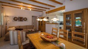 A cozy living room with a wooden dining table, a sofa, and a kitchen in the background. - Luxury Villa Inge 400 Beach large garden, private pool, air conditioning, BBQ, terrace, WLAN, whirlpool (Els Poblets, Alicante)