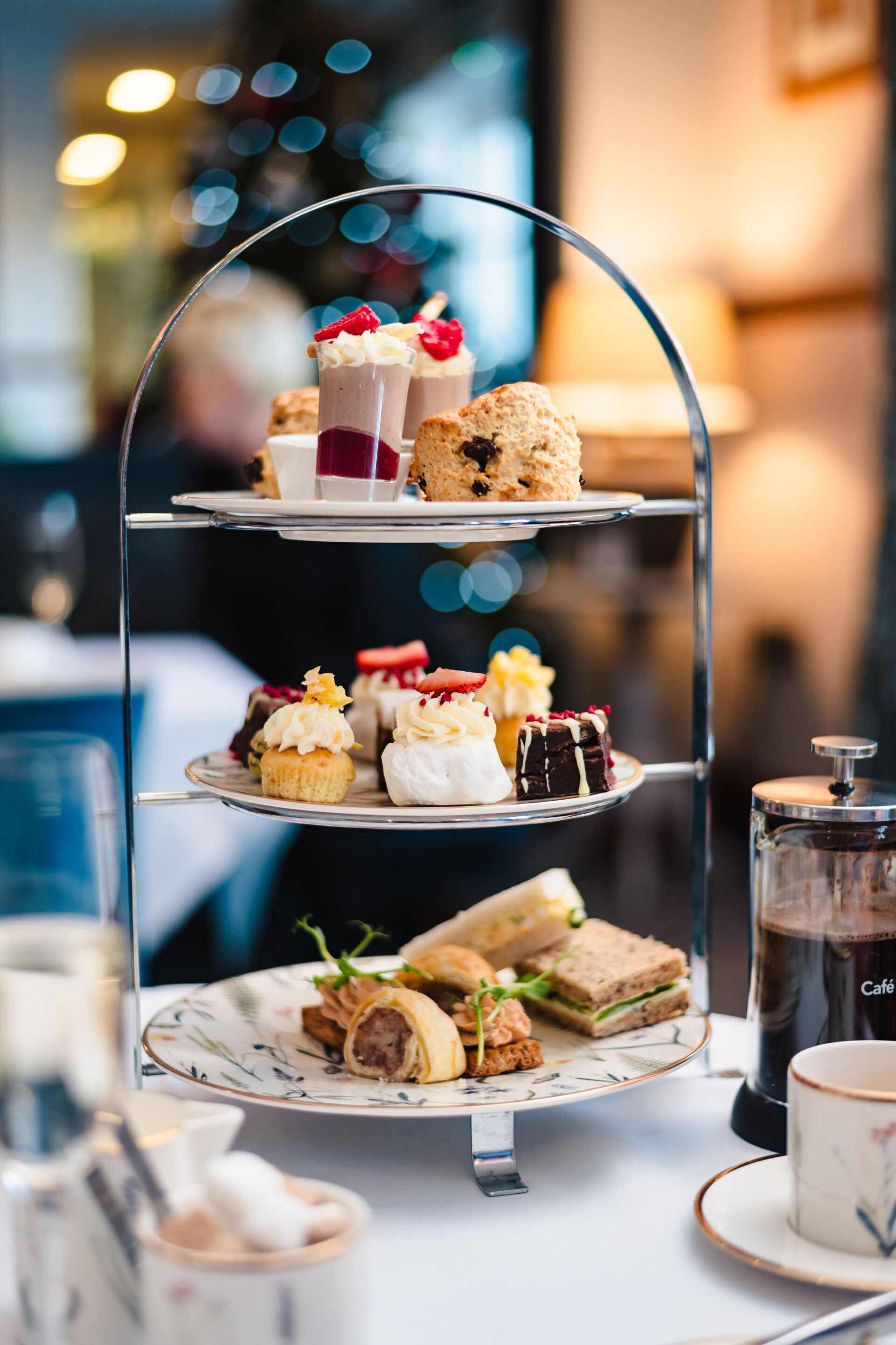 A three-tiered dessert stand with various pastries and sandwiches.
