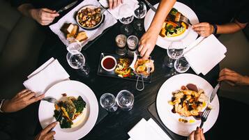 A group of people dining at a round table with various dishes and drinks.