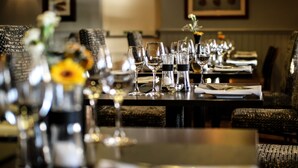 Un'ambientazione da ristorante con tavoli apparecchiati per la cena, con calici e bottiglie di vino.