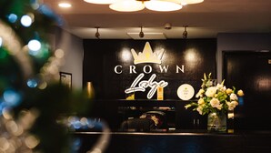 Una reception con una targa che riporta "Crown Lodge" e un simbolo decorativo a forma di corona.