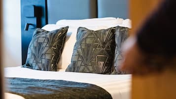 Una cama bien hecha con almohadones estampados y un cabecero oscuro.