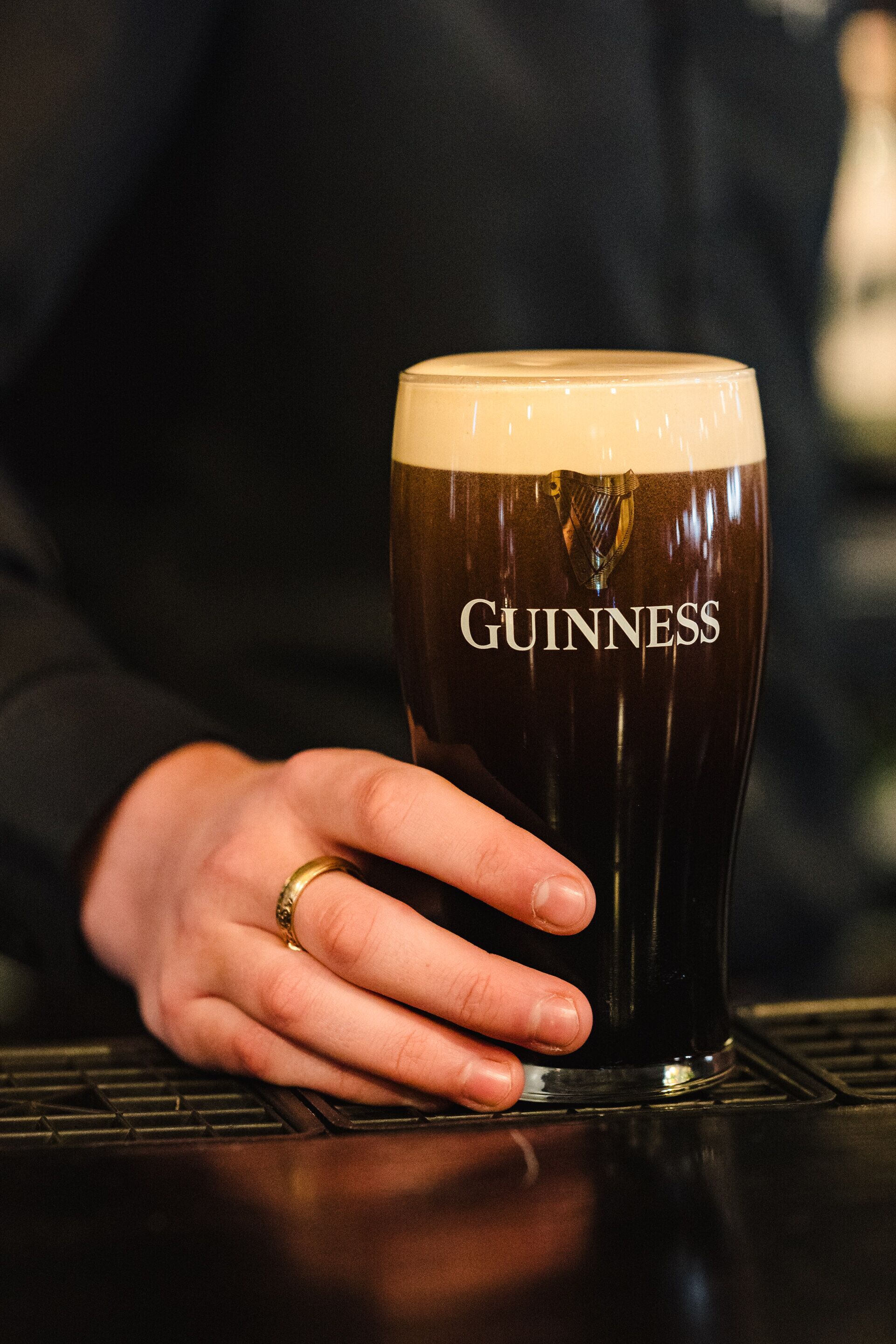 Eine Hand hält ein Guinness-Glas.