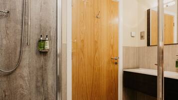 A modern bathroom with a shower, a wooden door, a sink, and a mirror.
