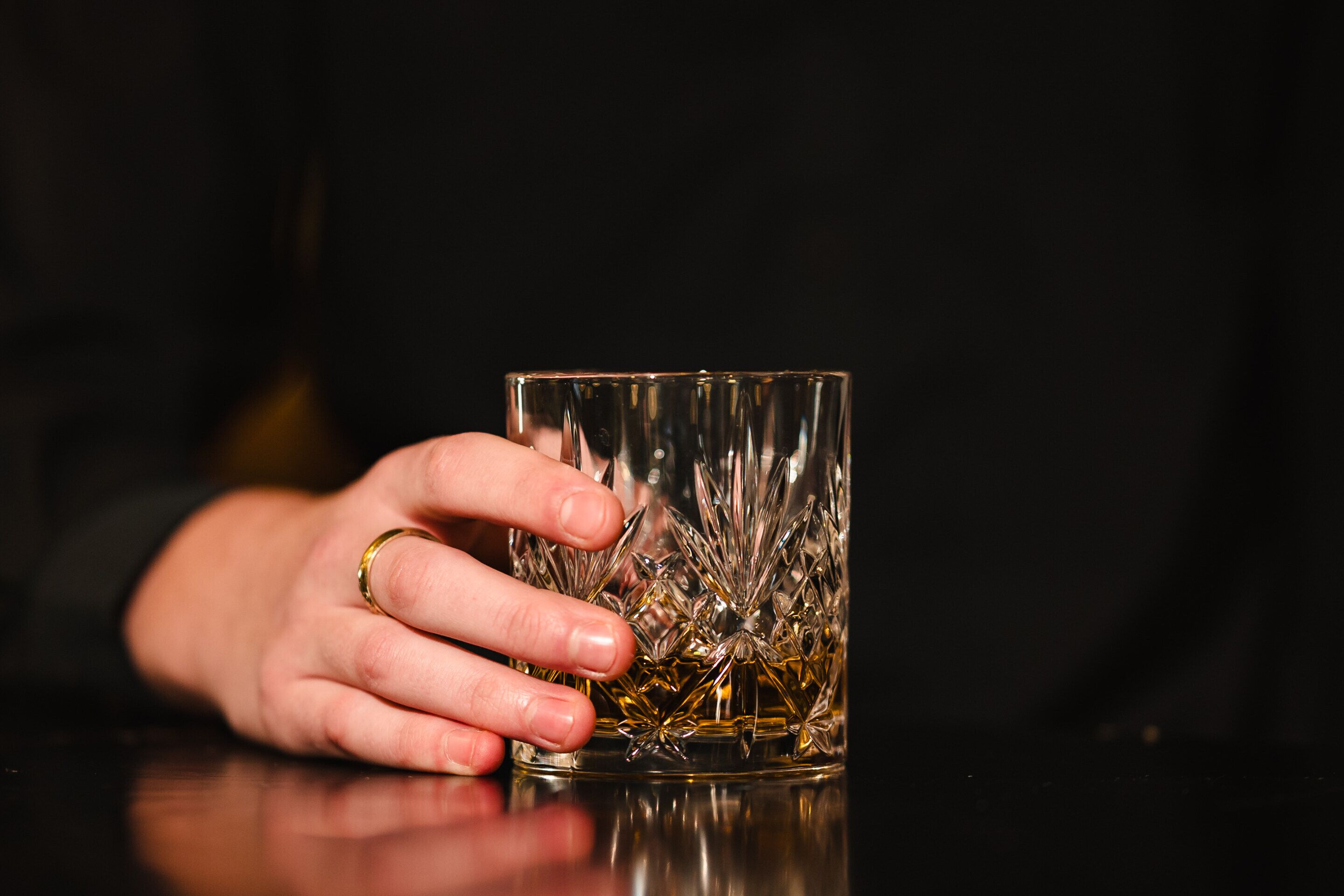 A hand holding a clear glass with a textured pattern.