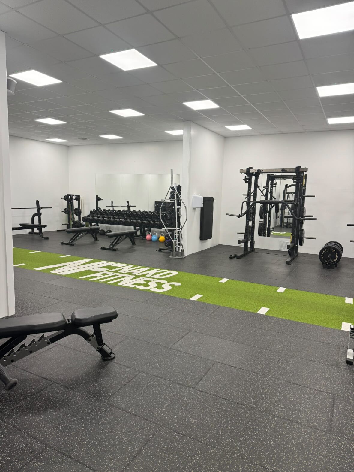 A gym with weightlifting equipment, a bench, and a green turf area labeled "Fitness".