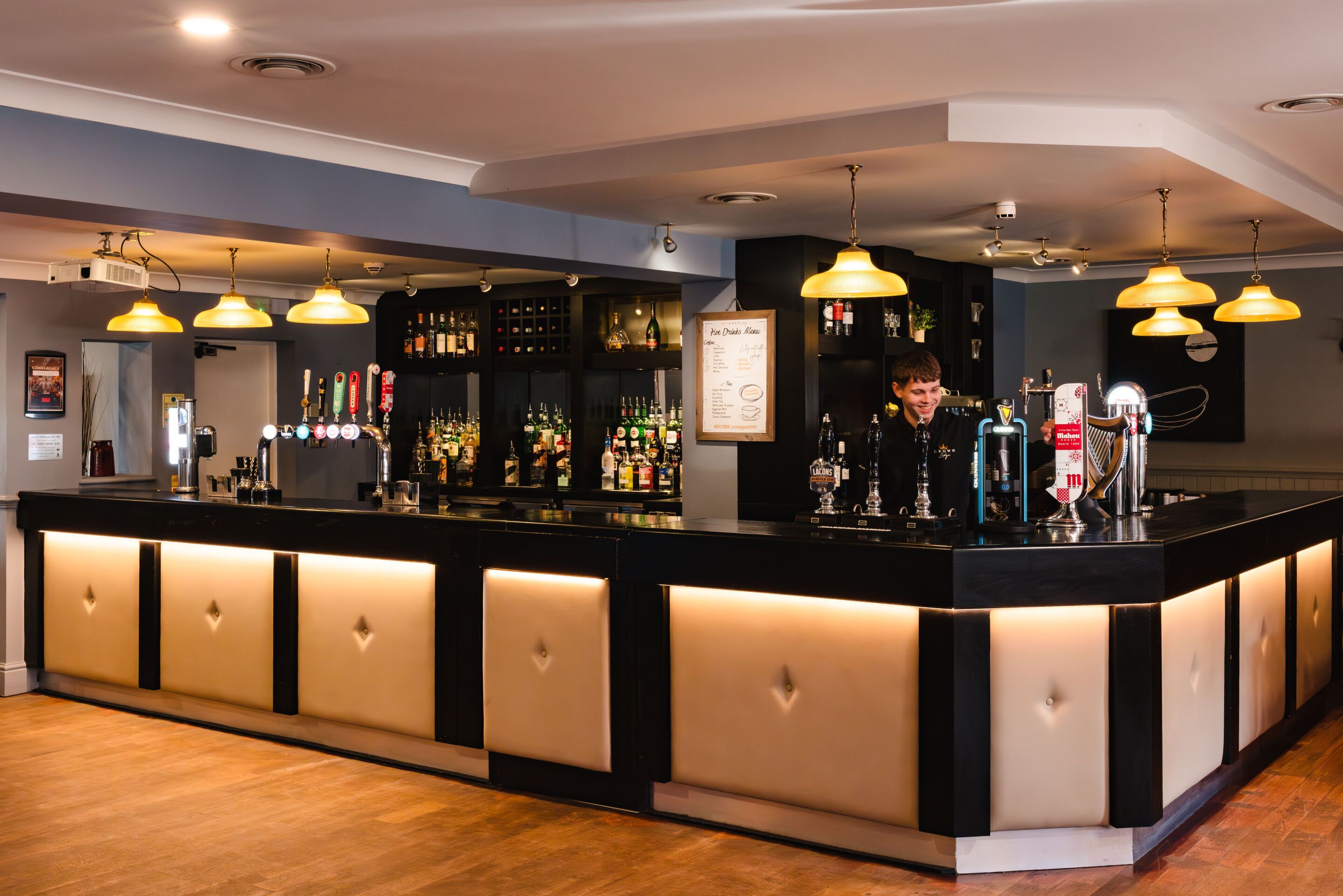 A bar area with a counter, multiple bottles, and hanging lights.