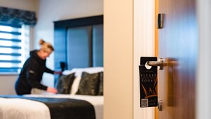 Una camera d'albergo con un letto, un comodino e una porta con un cartello.