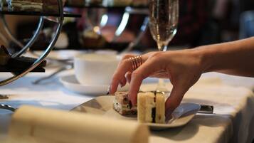 A hand placing a sandwich on a plate at a table with a glass of water and a cup.