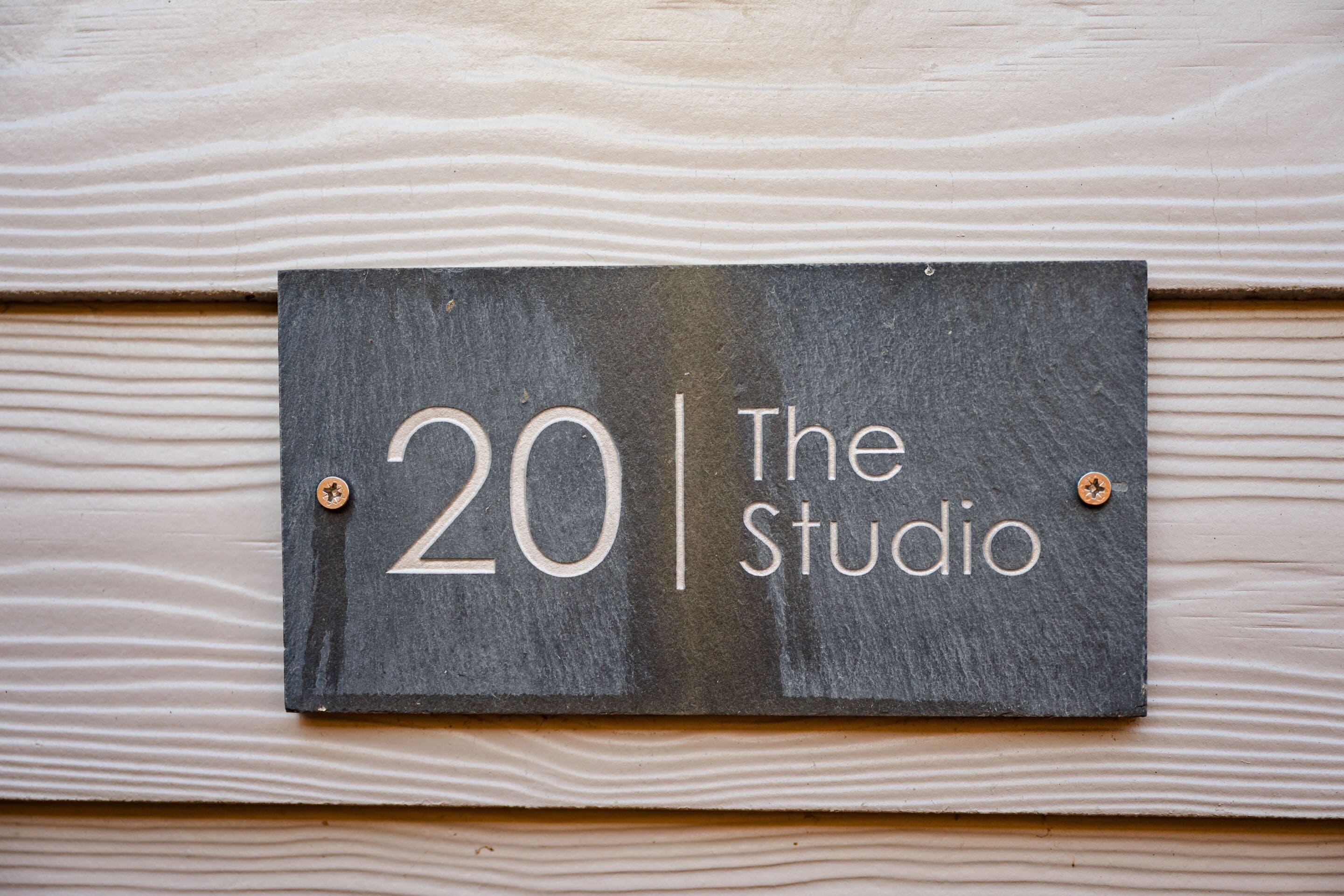 A sign with the number 20 and the text "The Studio" mounted on a wooden wall.