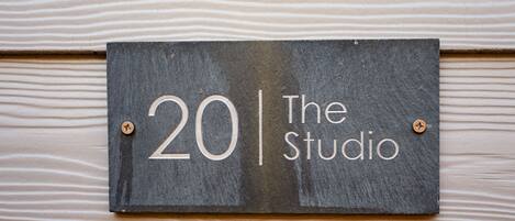 A sign with the number 20 and the text "The Studio" mounted on a wooden wall.