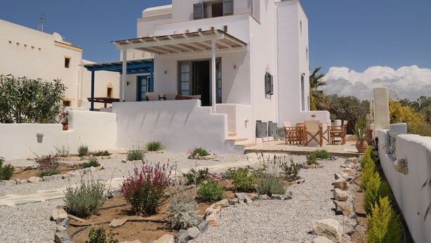 A white building with a covered patio and outdoor seating area.