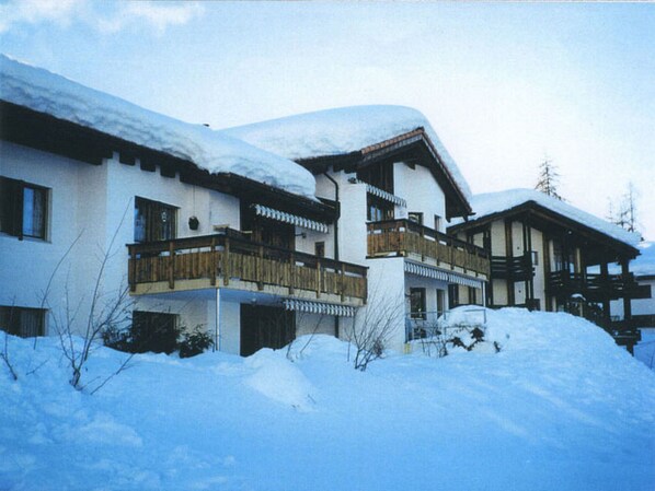 Un chalet a due piani con balconi in legno e un tetto innevato.