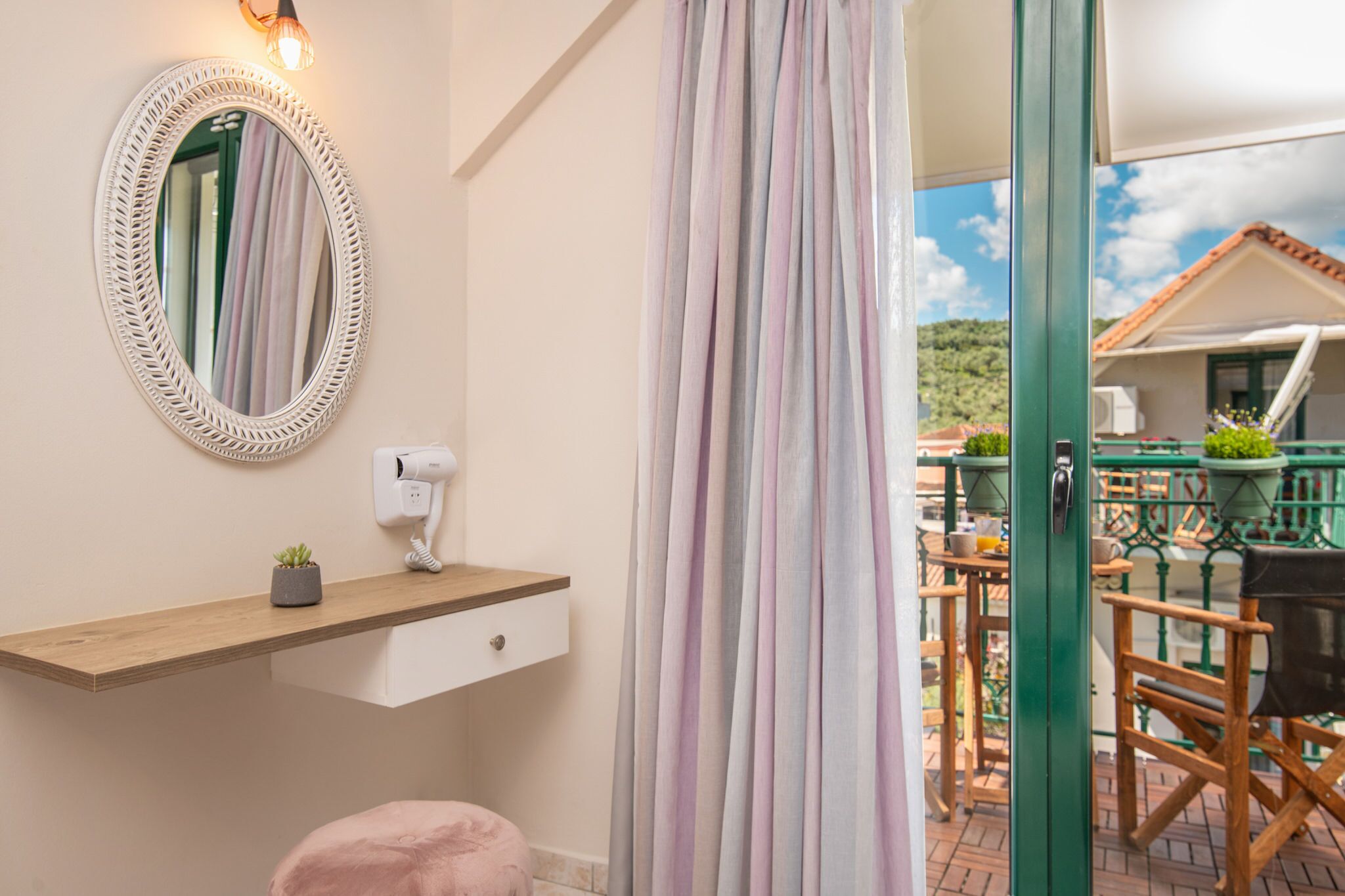 A bathroom with a wooden vanity, a mirror, a hairdryer, and a small plant.