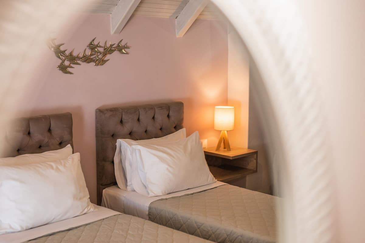 Une chambre d’hôtel avec deux lits, une table de chevet avec une lampe et un élément décoratif mural.