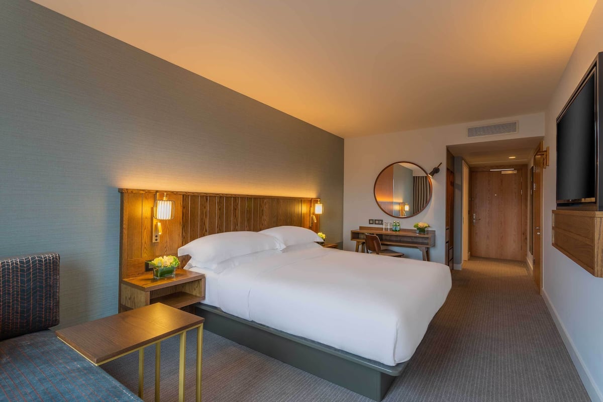 Een hotelkamer met een groot bed, nachtkastjes, een bureau en een spiegel.