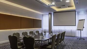A conference room with a large table, chairs, a projector screen, and a whiteboard.