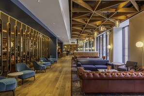 A modern hotel lobby with seating areas, a bar, and a kitchen in the background. - Hyatt Centric The Liberties Dublin (Dublin)
